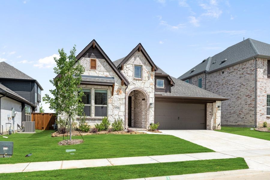 Two-story home with stone and brick exterior, arched entry, two-car garage, and green front lawn Two-story home with stone and brick exterior, arched entry, two-car garage, and green front lawn