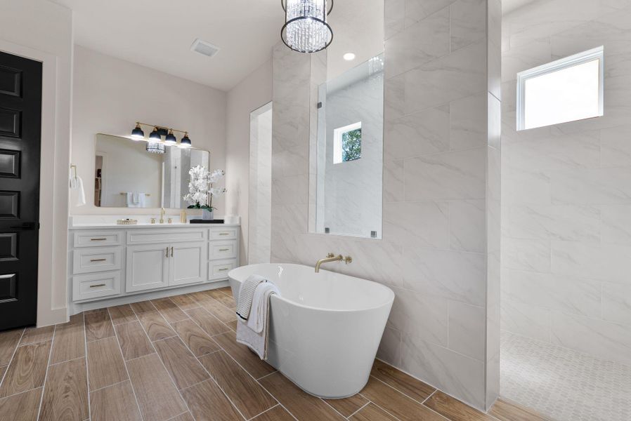 Indulge in this tranquil primary bathroom, featuring a freestanding tub and a spacious dual-vanity with refined fixtures.