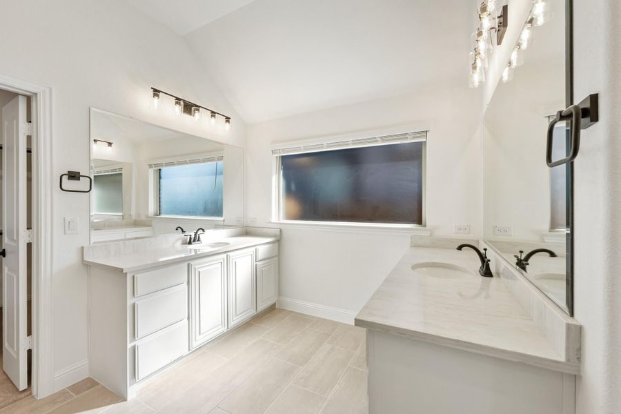 Bathroom with dual vanities, white cabinets, quartz countertops, and tile floors Bathroom with dual vanities, white cabinets, quartz countertops, and tile floors