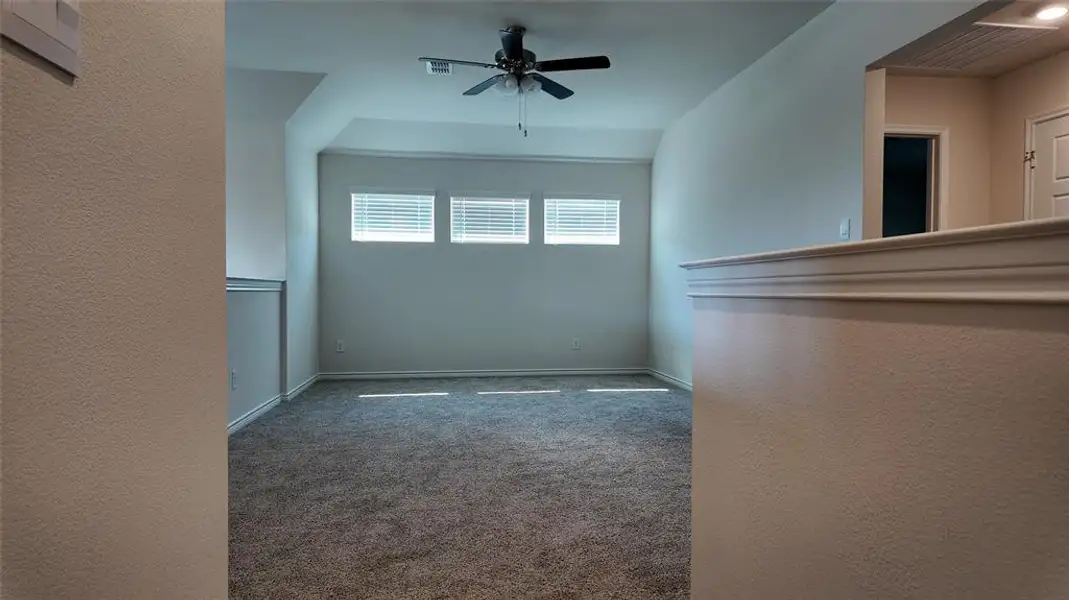 Carpeted spare room featuring ceiling fan and a textured wall