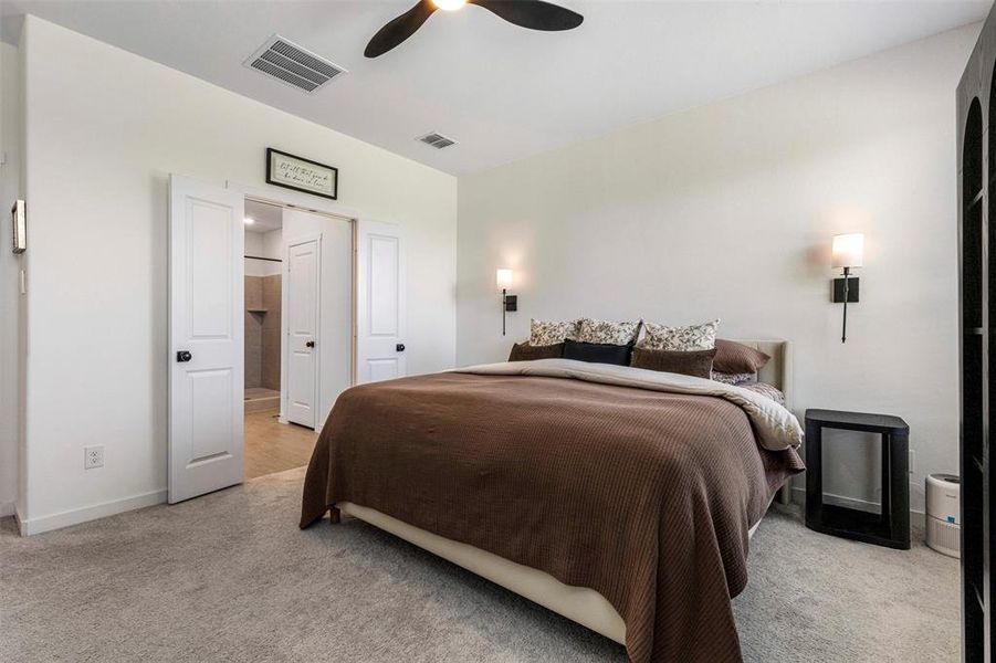 Spacious bedroom featuring light neutral walls and gray carpet flooring Spacious bedroom featuring light neutral walls and gray carpet flooring