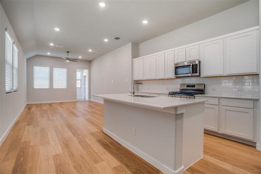 Kitchen featuring recessed lighting, a center island with sink, stainless steel appliances, white cabinets, and open floor plan