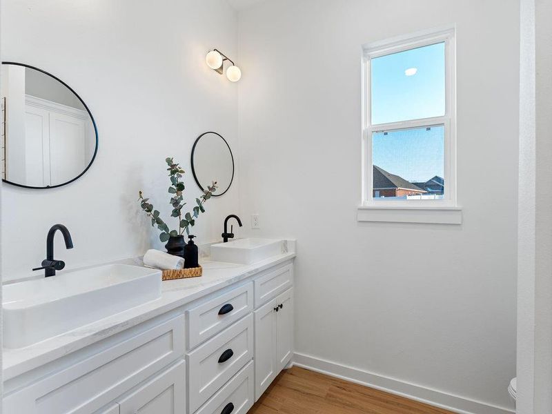 Full bathroom with double vanity and light wood finished floors