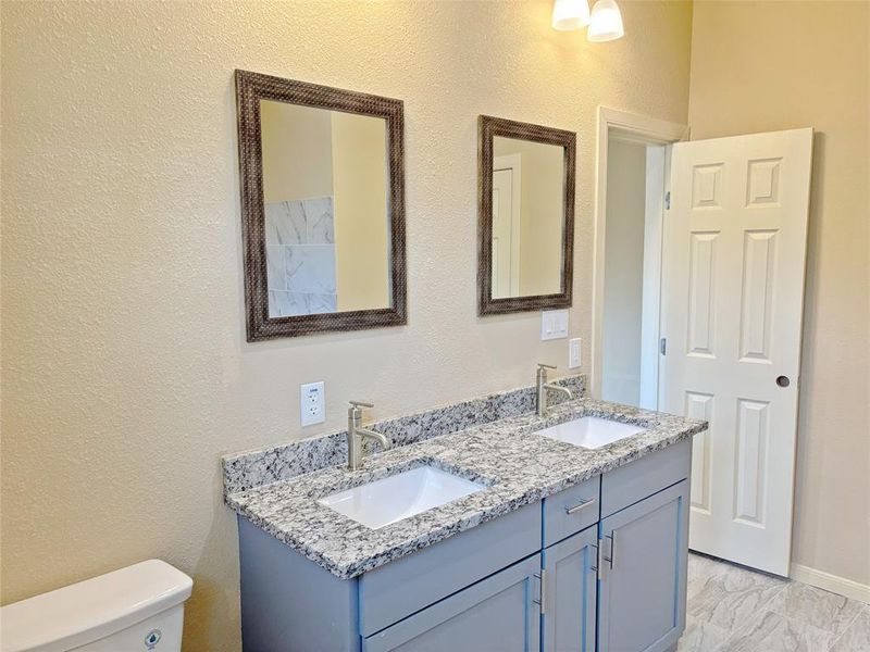 Bathroom with a textured wall and double vanity