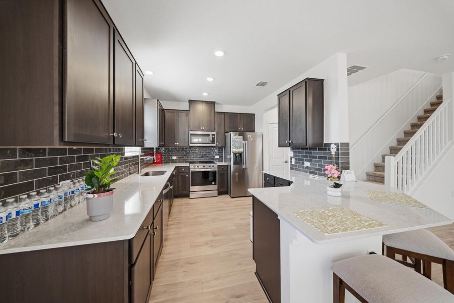 Culinary delights await in this modern kitchen with stainless steel appliances and an inviting breakfast bar. Culinary delights await in this modern kitchen with stainless steel appliances and an inviting breakfast bar.