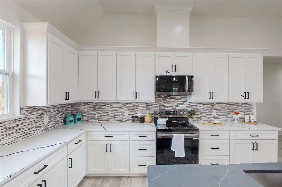 Kitchen featuring tasteful backsplash, stainless steel appliances, white cabinetry, and plenty of natural light