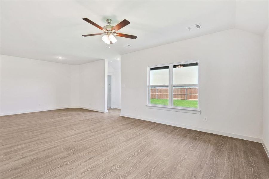 Empty room featuring light wood-type flooring, lofted ceiling, and ceiling fan