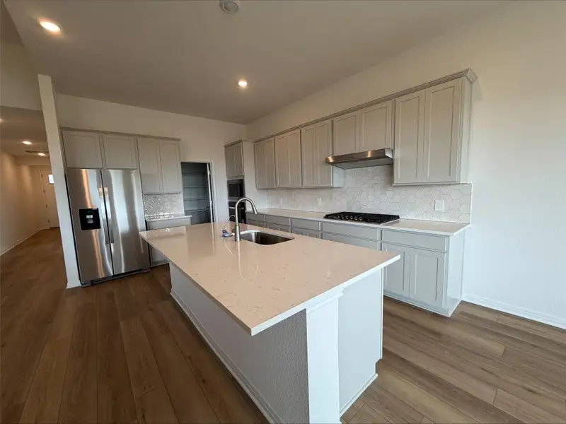 Kitchen featuring tasteful backsplash, appliances with stainless steel finishes, light stone counters, dark wood-type flooring, and recessed lighting Kitchen featuring tasteful backsplash, appliances with stainless steel finishes, light stone counters, dark wood-type flooring, and recessed lighting