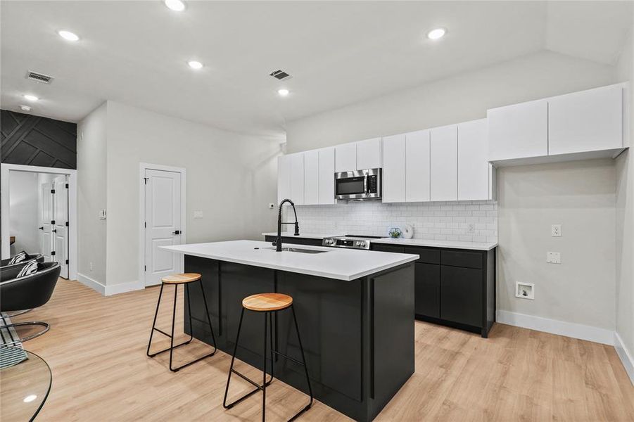 Kitchen featuring a kitchen island with sink, sink, light wood-type flooring, and appliances with stainless steel finishes