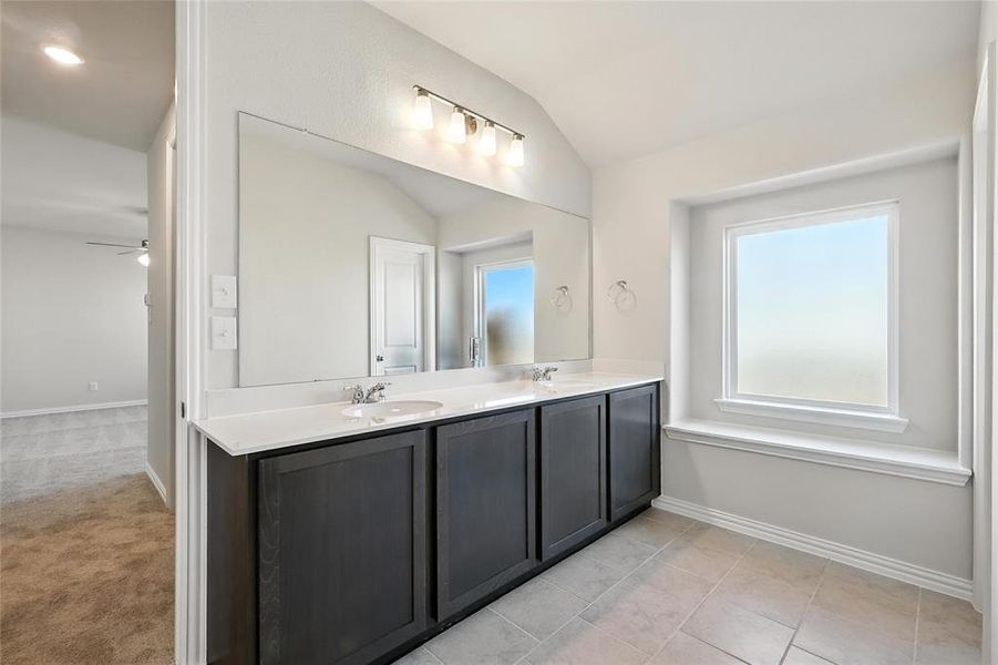 Full bathroom featuring double vanity, lofted ceiling, and a ceiling fan Full bathroom featuring double vanity, lofted ceiling, and a ceiling fan