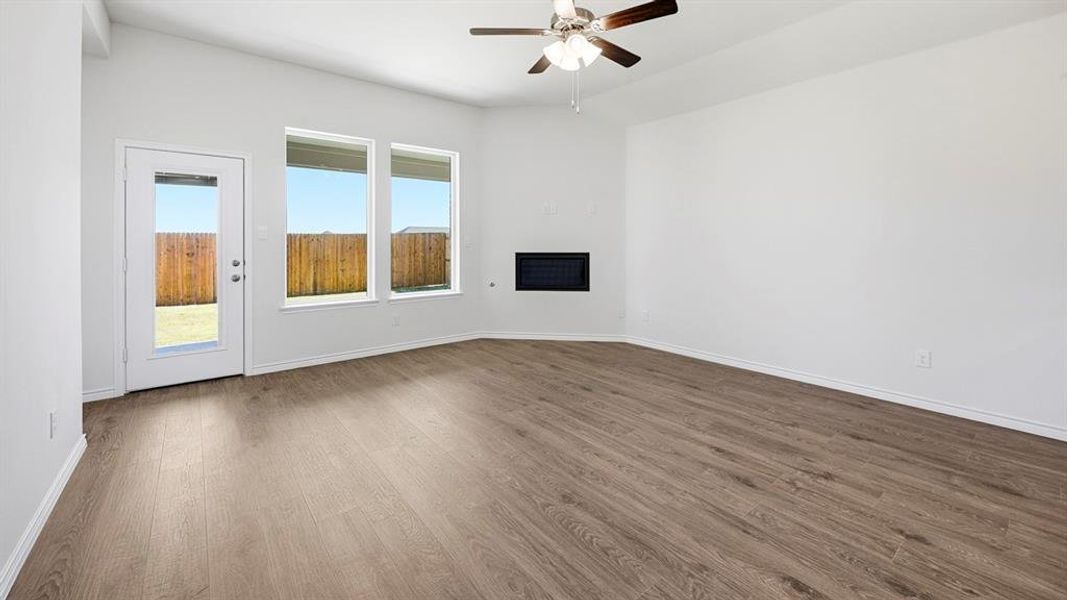 Unfurnished living room with wood finished floors, a ceiling fan, and a fireplace