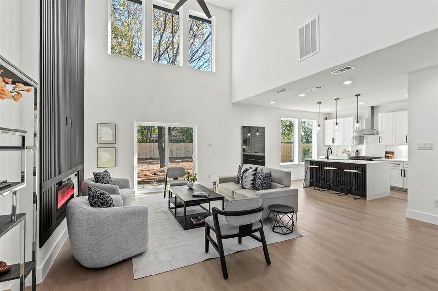 Living room with plenty of natural light, light wood-type flooring, and a towering ceiling