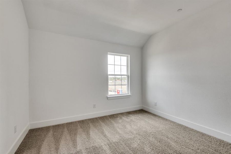 Carpeted empty room featuring lofted ceiling