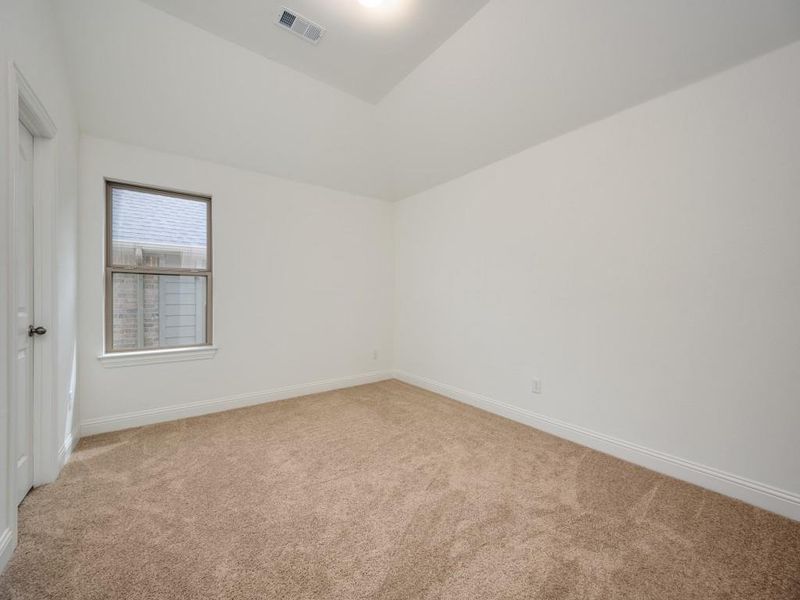 Spare room with lofted ceiling, baseboards, light colored carpet, and visible vents