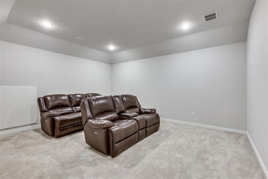 Home theater room featuring light carpet