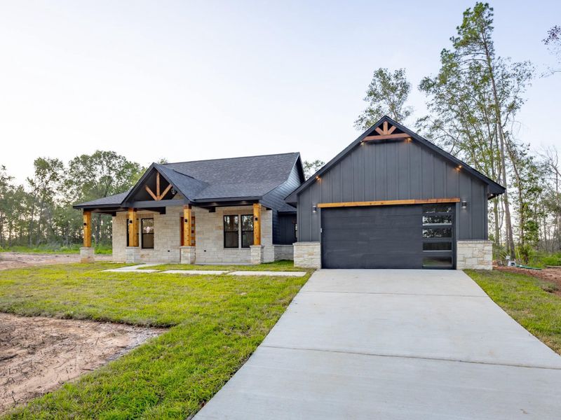 A spacious concrete driveway leads to the modern black-paneled garage door with glass inserts—both functional and stylish for today’s lifestyle. A spacious concrete driveway leads to the modern black-paneled garage door with glass inserts—both functional and stylish for today’s lifestyle.