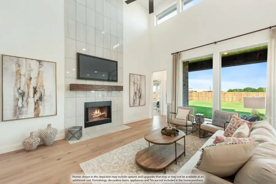Living room with two-story tiled fireplace, hardwood floors, and large windows overlooking backyard