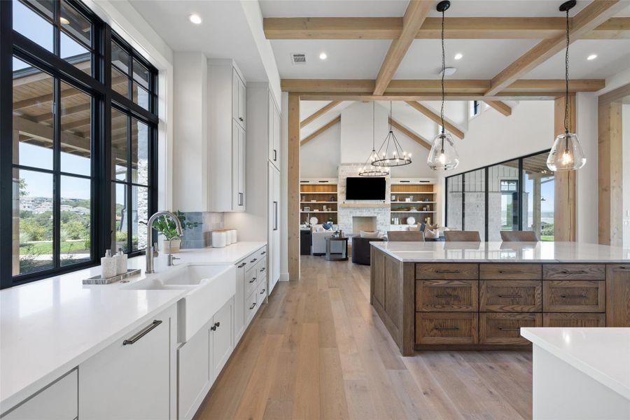 Kitchen with beam ceiling, white cabinets, pendant lighting, light stone counters, and a fireplace