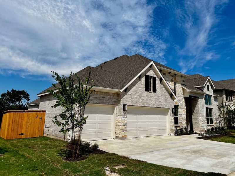 View of front facade featuring roof with shingles, driveway, brick siding, and stone siding View of front facade featuring roof with shingles, driveway, brick siding, and stone siding