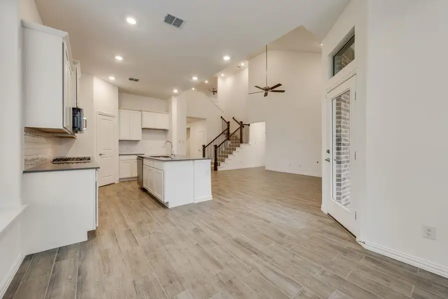 Kitchen featuring a towering ceiling, an island with sink, light hardwood / wood-style floors, white cabinets, and ceiling fan