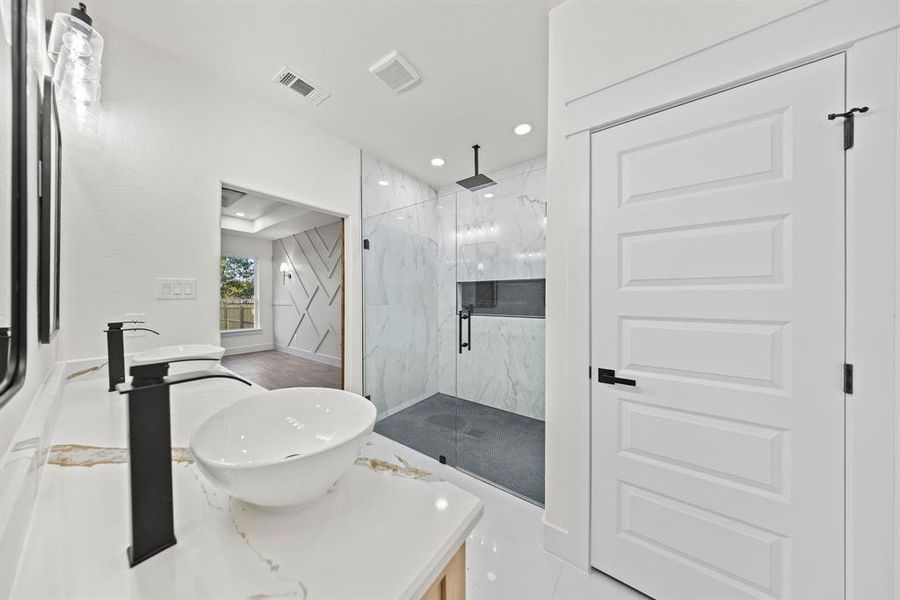 Bathroom featuring vanity, a marble finish shower, and recessed lighting