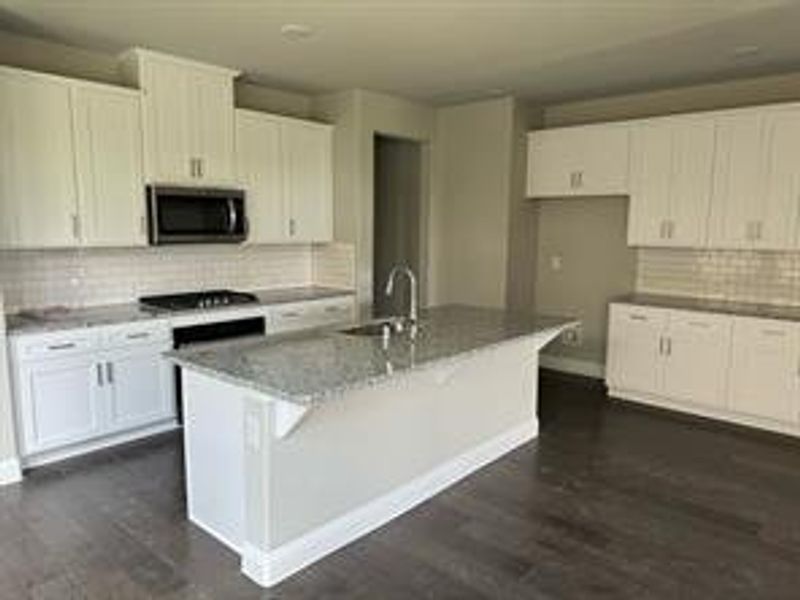 Kitchen with white cabinets, an island with sink, and gas stovetop