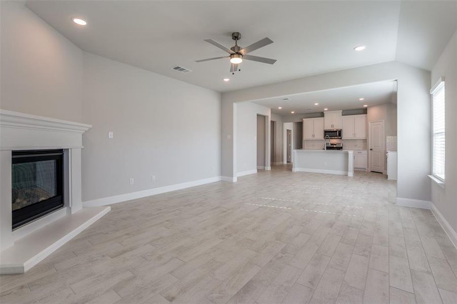 Spacious living area featuring wood-finish tile flooring and a white mantel fireplace