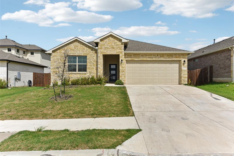 View of front facade featuring stone siding, driveway, and an attached garage View of front facade featuring stone siding, driveway, and an attached garage