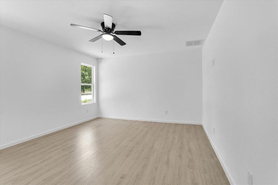 Empty room with ceiling fan and light hardwood / wood-style flooring