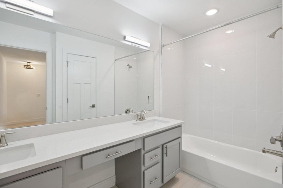 Full bathroom with double vanity and bathing tub / shower combination