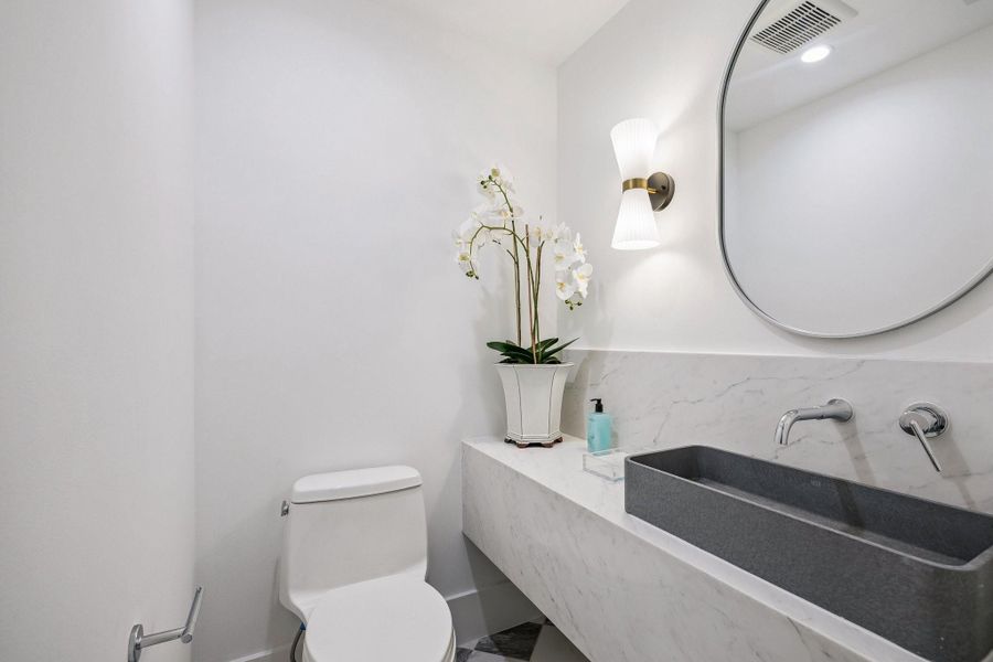 Second Powder Room located next to MUD Area to service the Back Covered Lanai with a 24 x 24 Checkerboard Matte Porcelain Tile in Calcutta and Amani Grey.  Floating Slab Quartz Counter and Backsplash, Rectangular Concrete Vessel Sink, Wall Mounted Widespread Bathroom Faucet in Polished Chrome, Oval Mirror and a White Striped Glass Sconce.