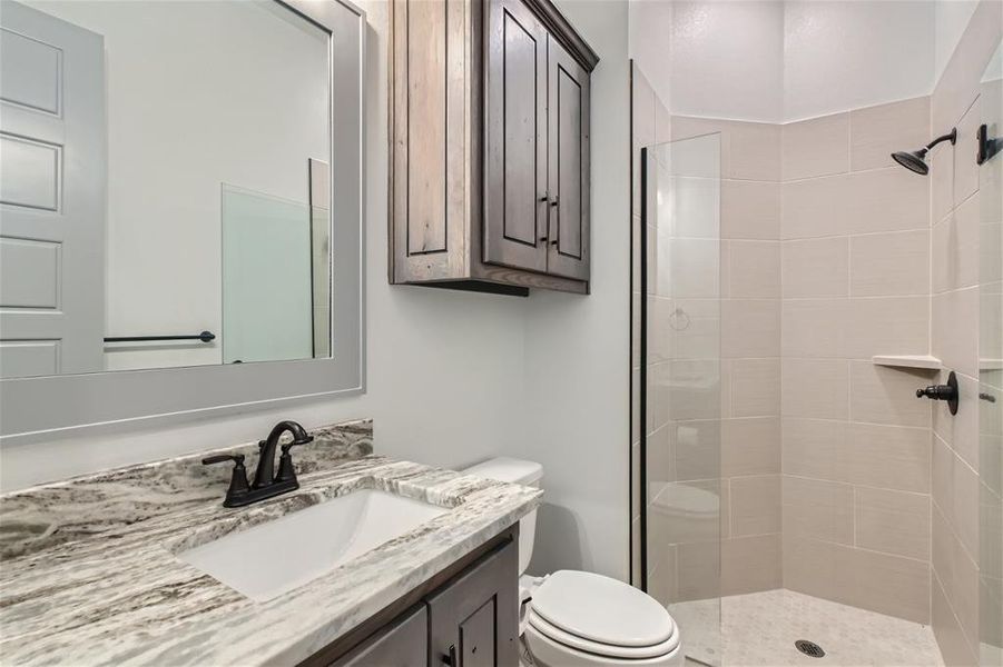 Bathroom with vanity, toilet, and a tile shower