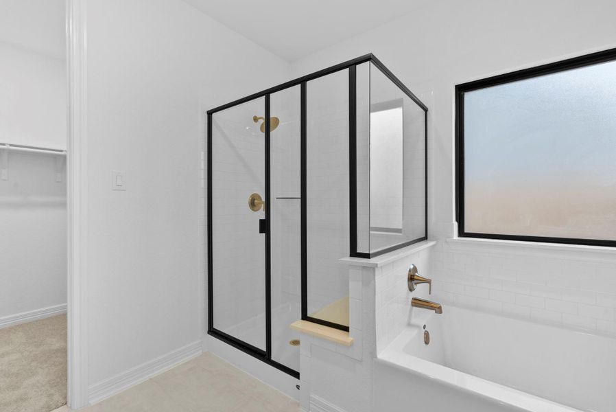 Modern and serene, the walk-in shower showcases a black-framed enclosure, classic white subway tile, and subtle gold details.