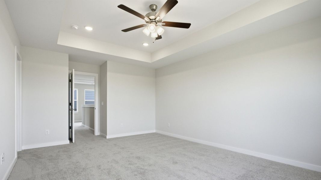 Bedroom with tray ceiling, ceiling fan, and entry to second floor Bedroom with tray ceiling, ceiling fan, and entry to second floor