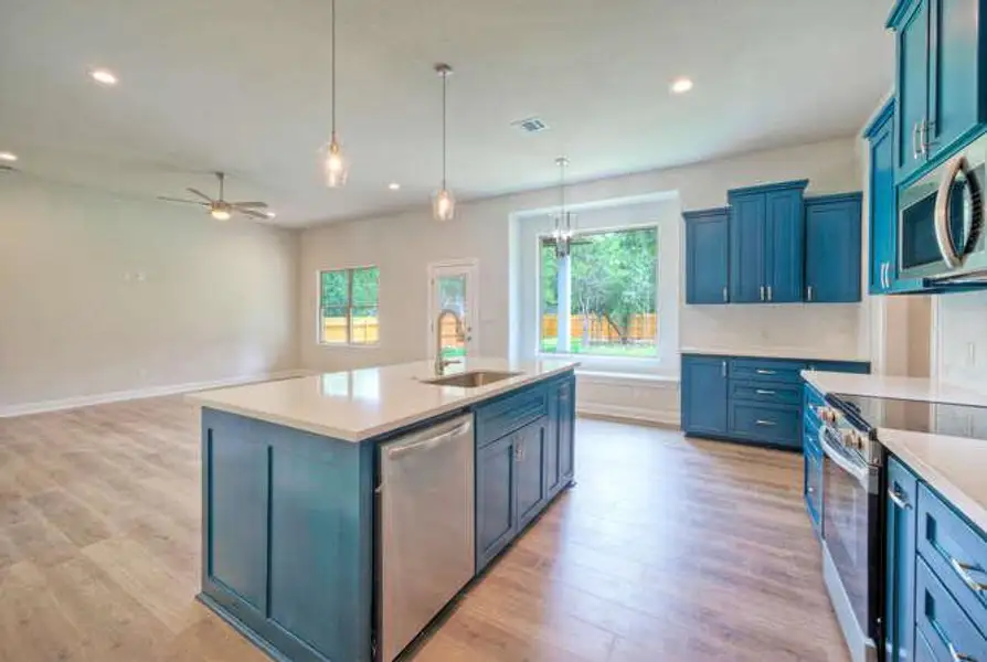 Kitchen with stainless steel appliances, light wood finished floors, light countertops, pendant lighting, and recessed lighting