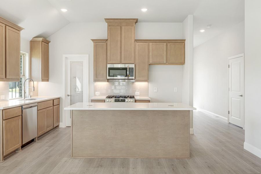 Kitchen with light wood cabinets, center island, stainless steel appliances, and light hardwood floors