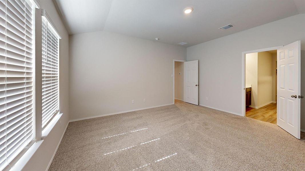 Unfurnished bedroom featuring vaulted ceiling, light carpet, connected bathroom, and recessed lighting