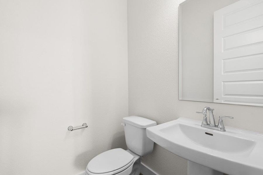 Half bathroom featuring toilet and a textured wall Half bathroom featuring toilet and a textured wall