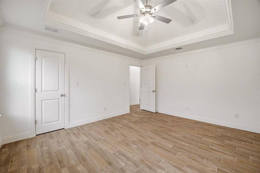This room features light-colored tile flooring, white walls, and a tray ceiling with a ceiling fan