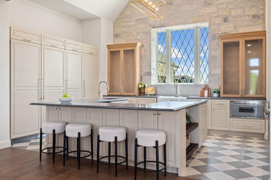 Kitchen with an island with sink, a breakfast bar, white cabinetry, light flooring, and lofted ceiling