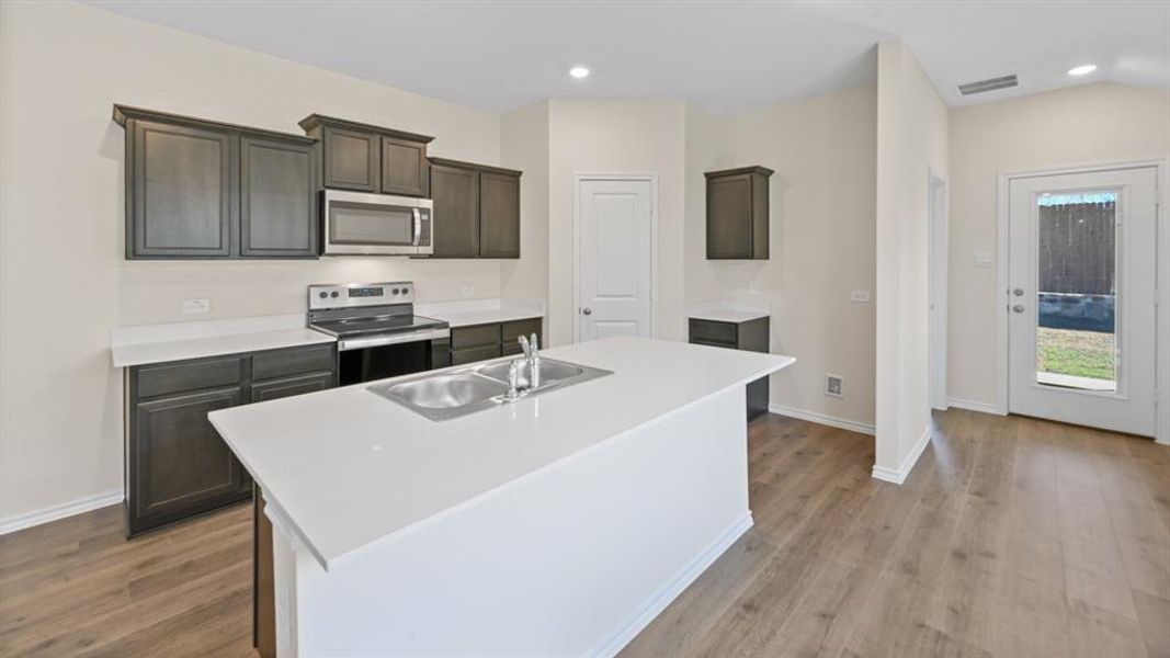Modern kitchen featuring an expansive center island with an integrated double basin sink and a stainless steel faucet