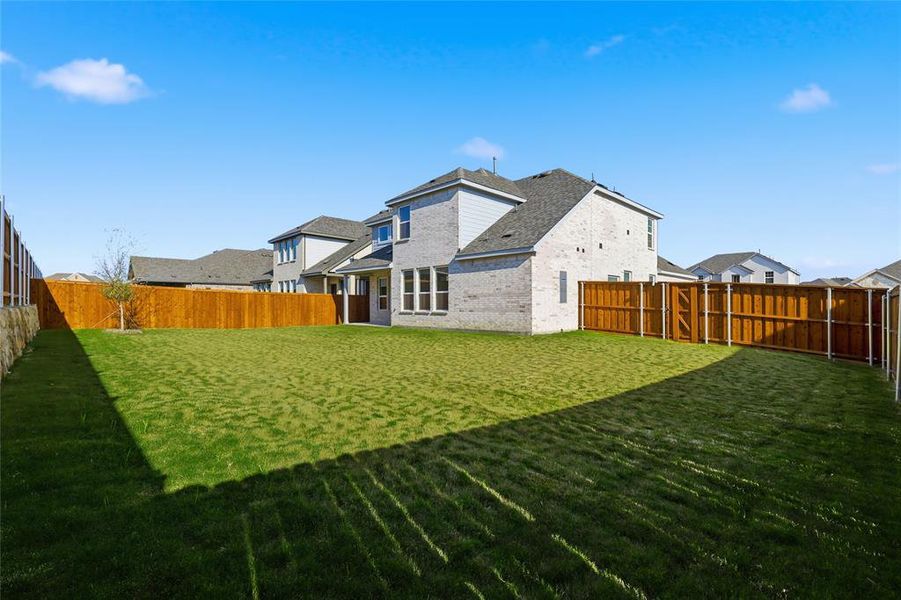 Rear view of house with a fenced backyard and brick siding