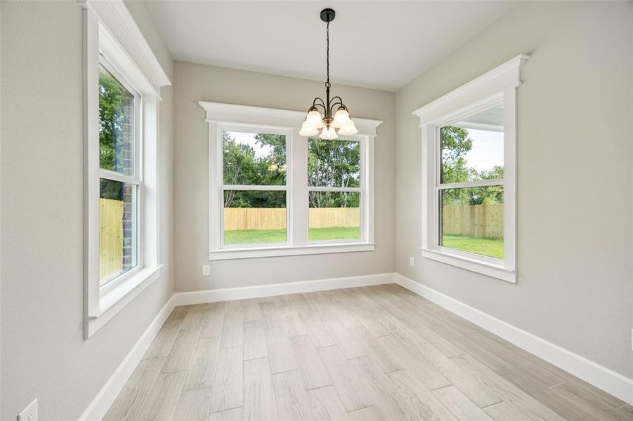 Unfurnished dining area featuring a chandelier and light wood-style floors Unfurnished dining area featuring a chandelier and light wood-style floors