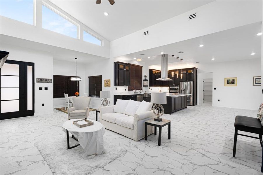 Living area with light marble finish flooring, high vaulted ceiling, recessed lighting, and a ceiling fan