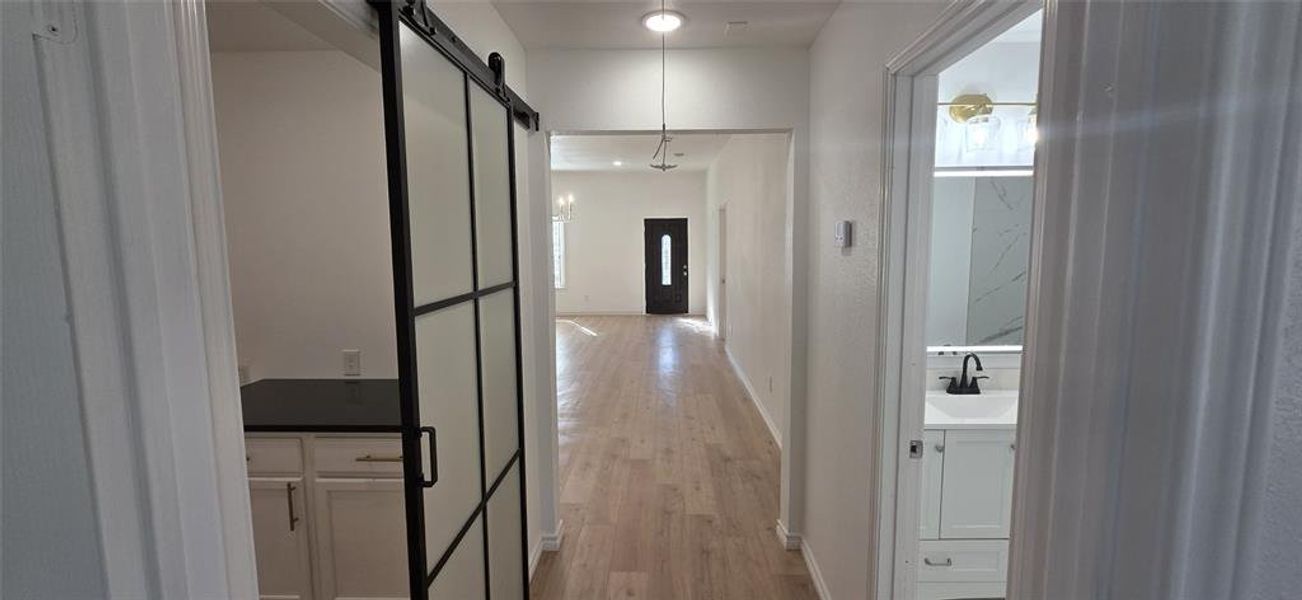 Hallway with a barn door and light wood-type flooring