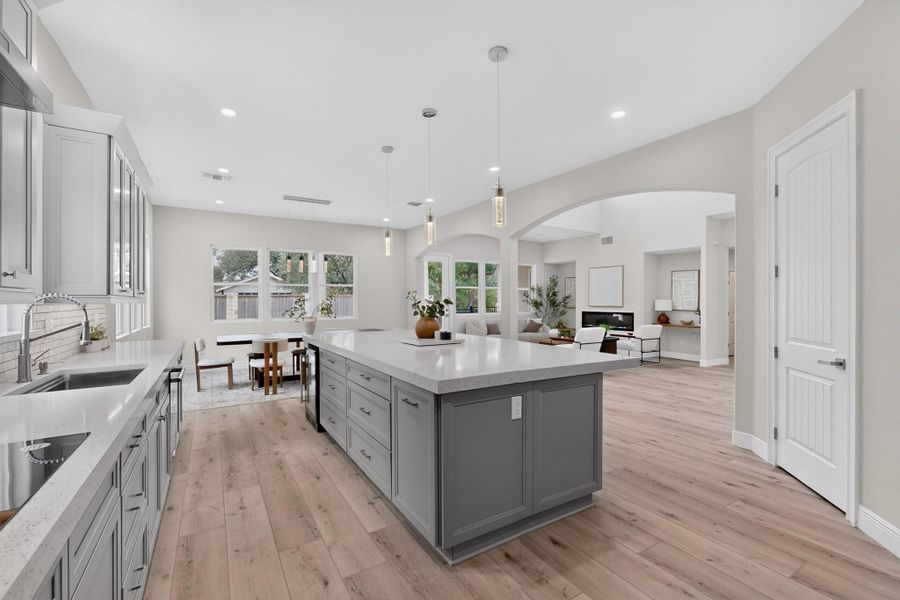 Hardwood floors and stone countertops anchor this airy, open-concept kitchen under recessed lighting.