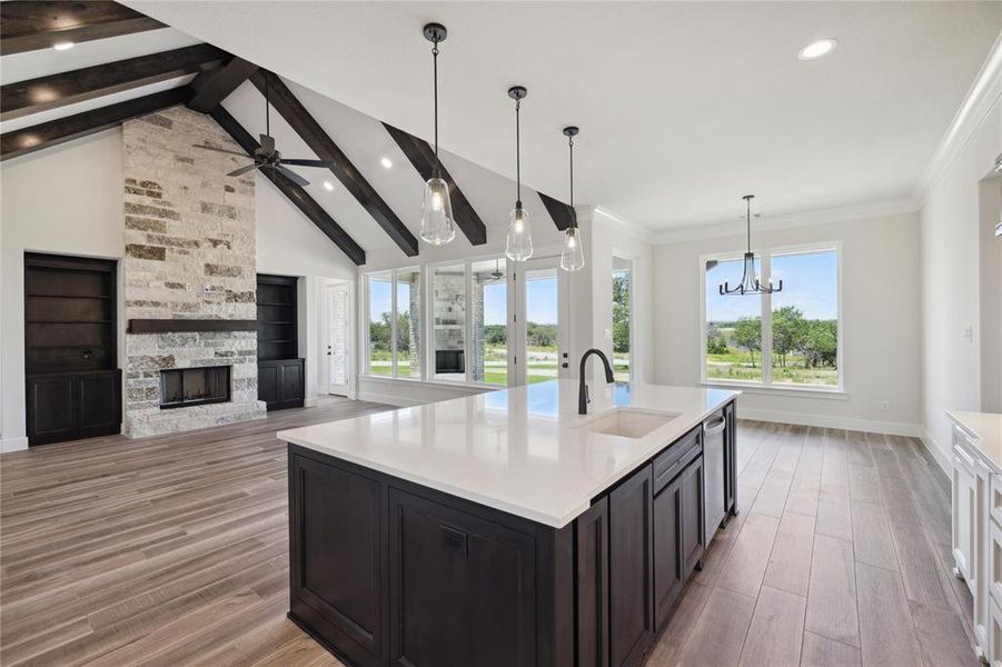 Kitchen featuring sink, a stone fireplace, beamed ceiling, and light wood-type flooring