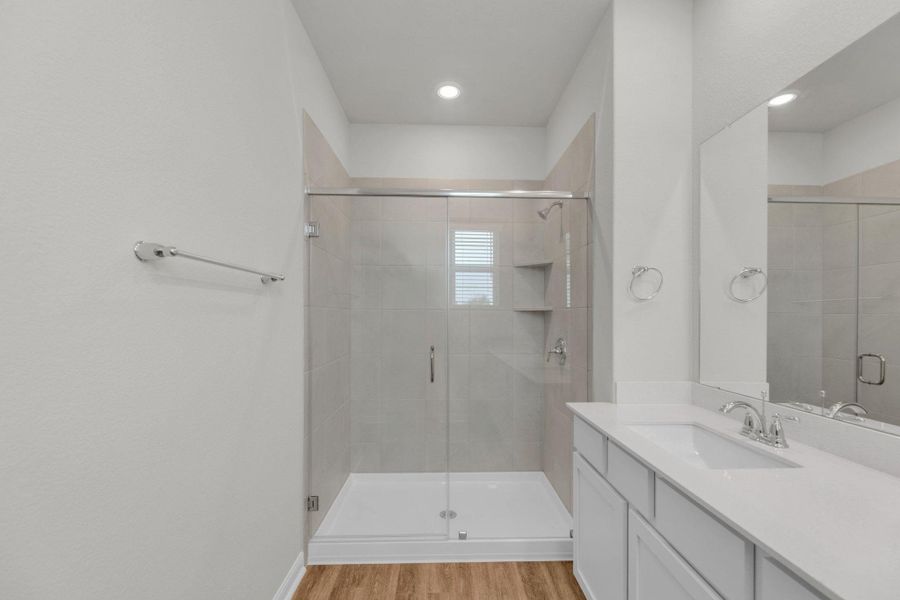 Full bath featuring a shower stall, vanity, and light wood finished floors