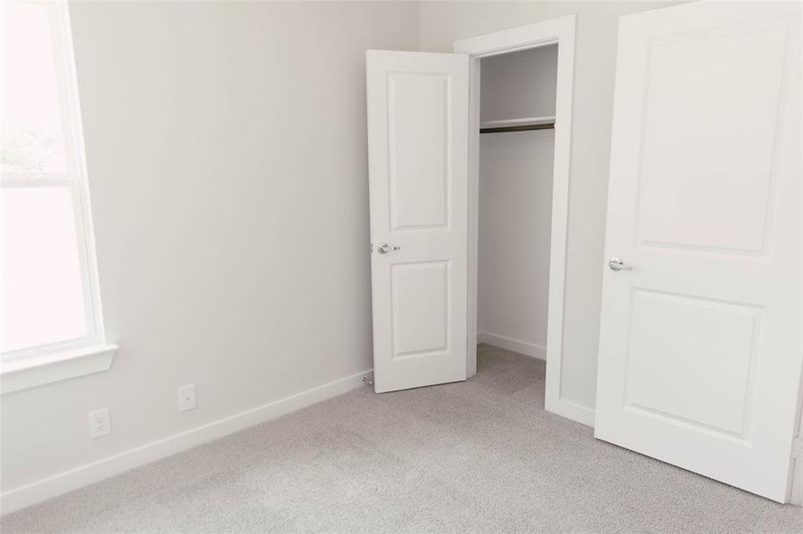 Unfurnished bedroom featuring light carpet and a closet