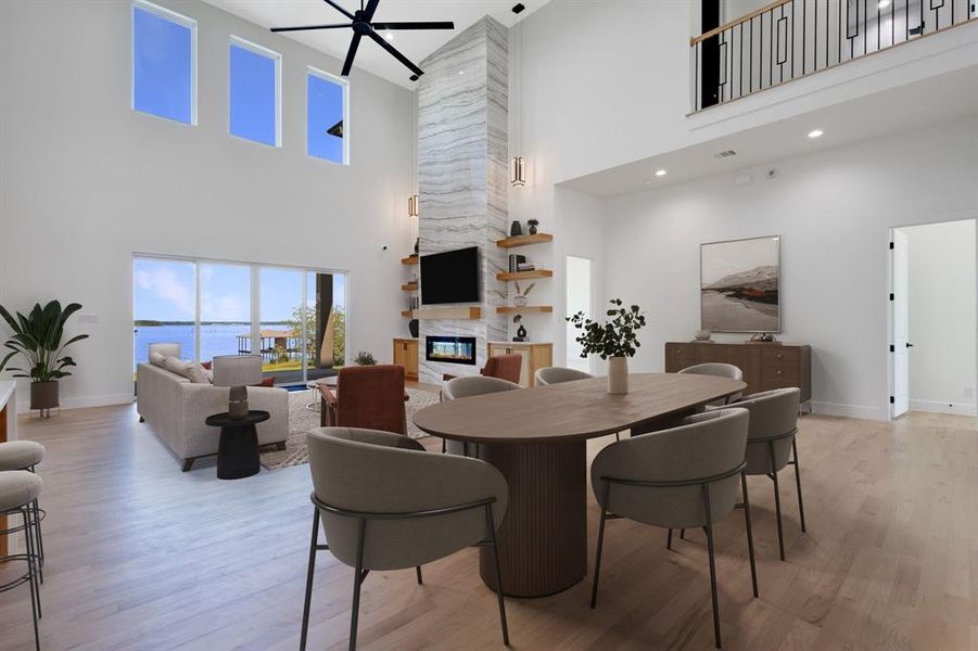 Spacious open-concept living area featuring a double-height ceiling, wood-finish flooring, and a contemporary linear fireplace